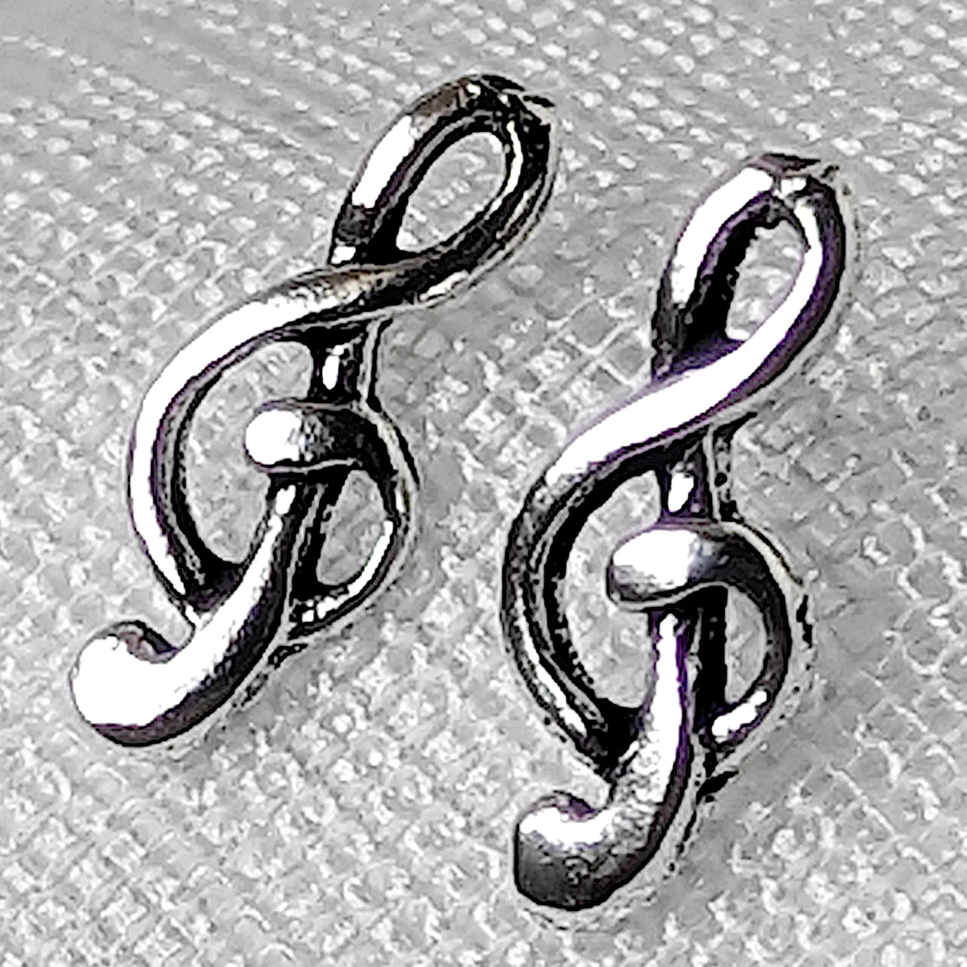 Nahaufnahme von zwei filigranen Notenschlüssel Ohrsteckern aus glänzendem 925 Sterling Silber