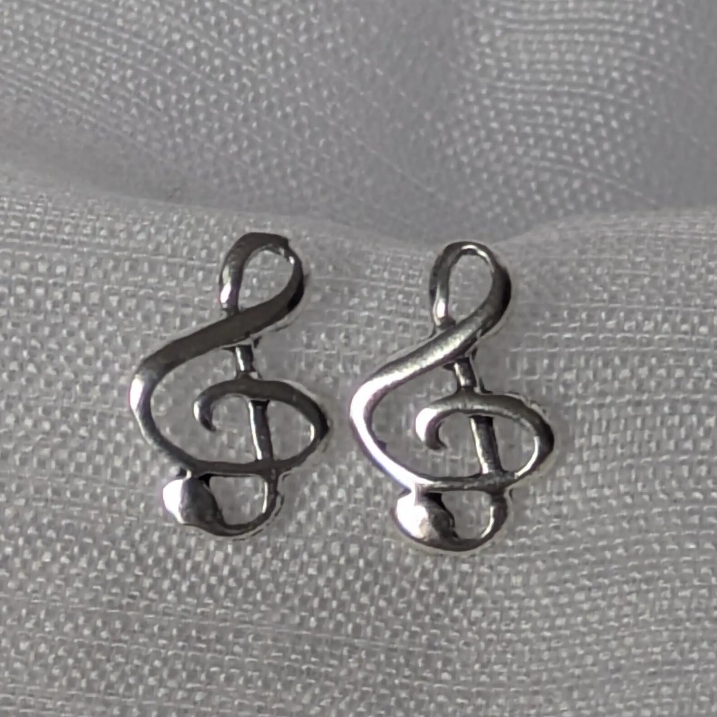 Detailansicht der filigranen Notenschlüssel-Ohrstecker aus poliertem 925 Silber.