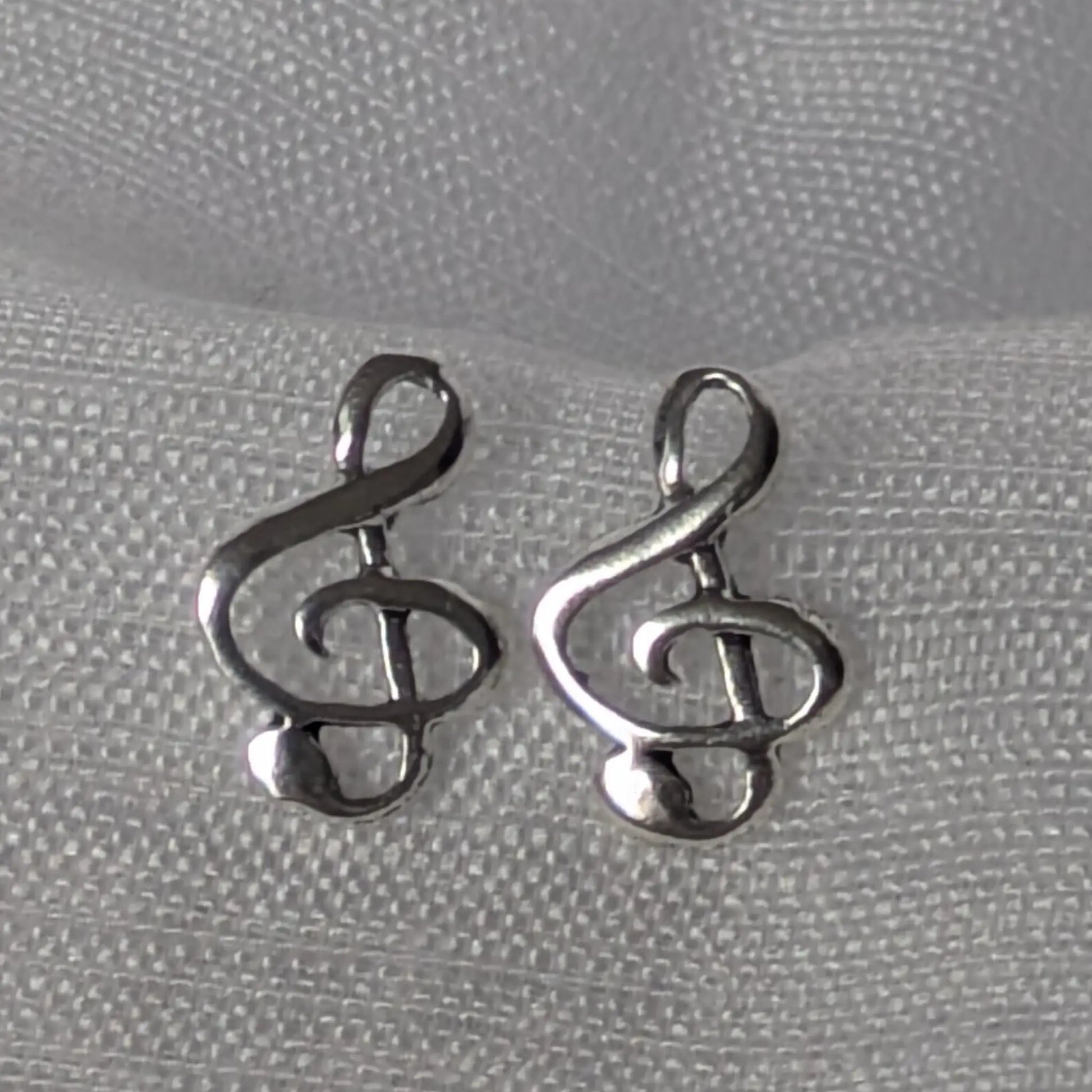 Detailansicht der filigranen Notenschlüssel-Ohrstecker aus poliertem 925 Silber.