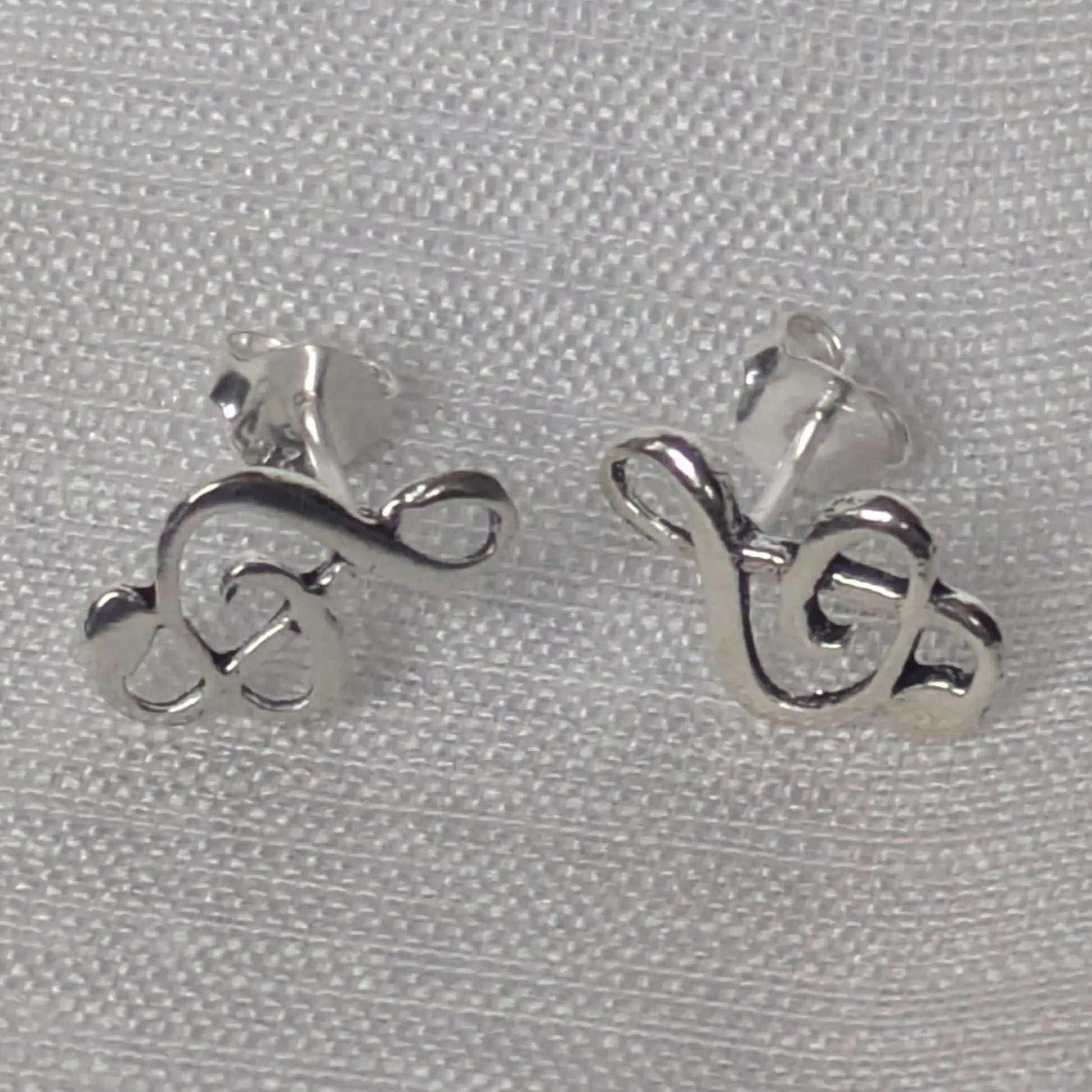 Paar silberne Musik-Ohrstecker in Violinschlüssel-Form in der Vorderansicht.
