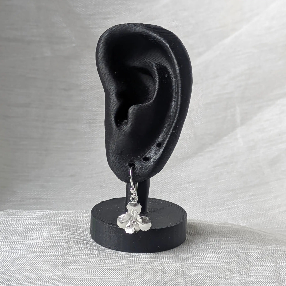 Florale Silber-Ohrhänger stilvoll präsentiert hängend an einem schwarzen Ohr-Display.