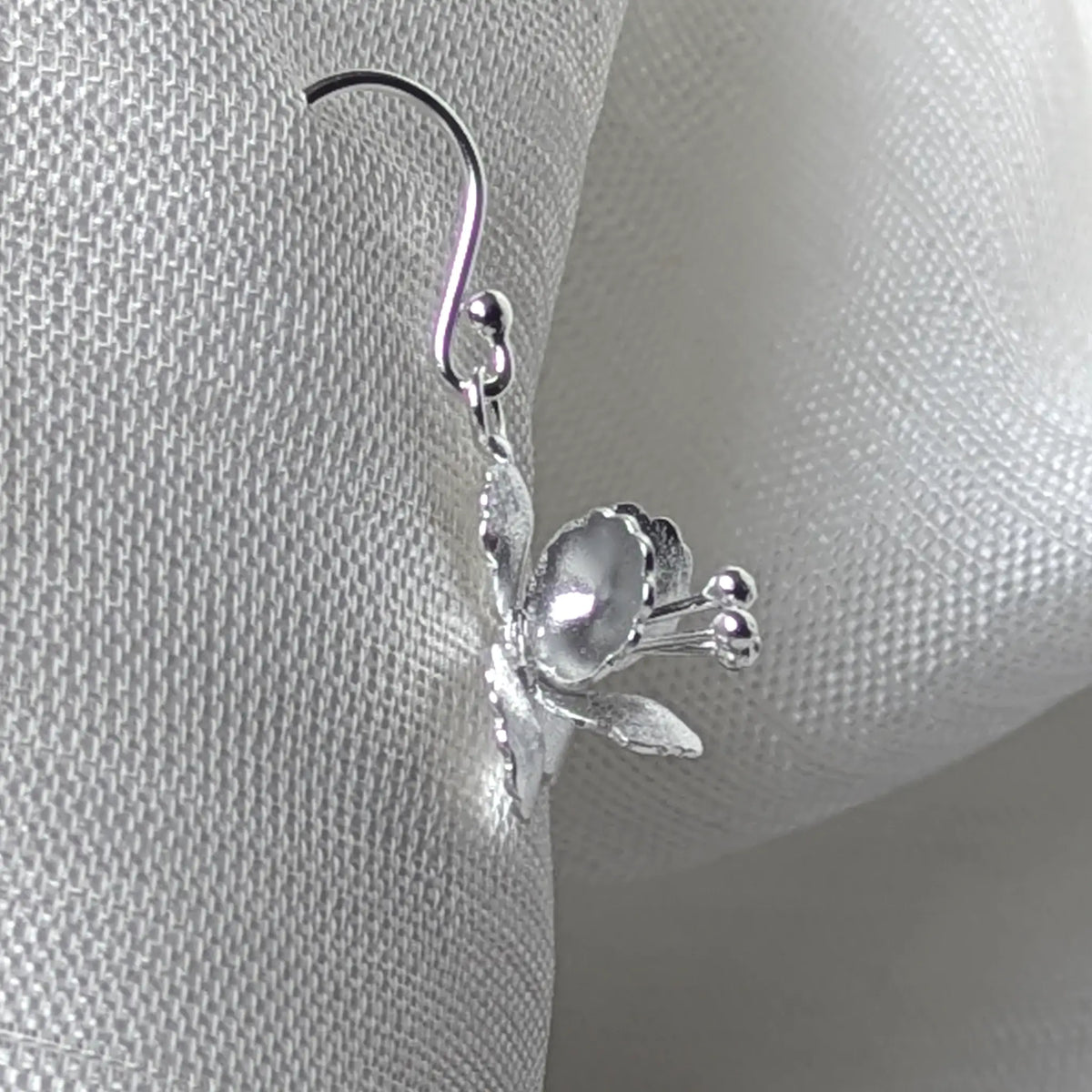 Seitenansicht der floralen Silber-Ohrringe am geschwungenen Ohrhaken.