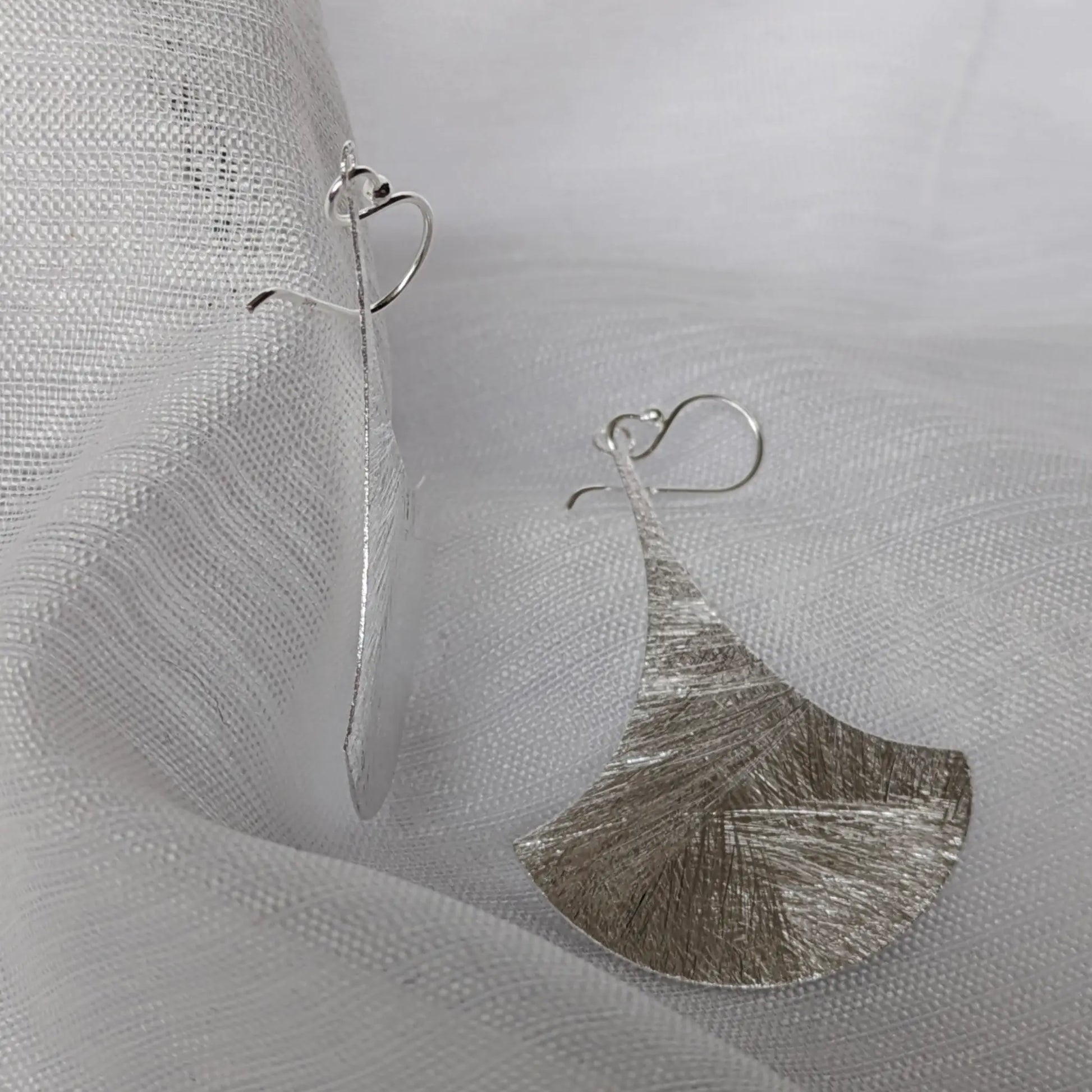 Seitenansicht der flachen, elegant geschwungenen Silber-Ohrhänger.
