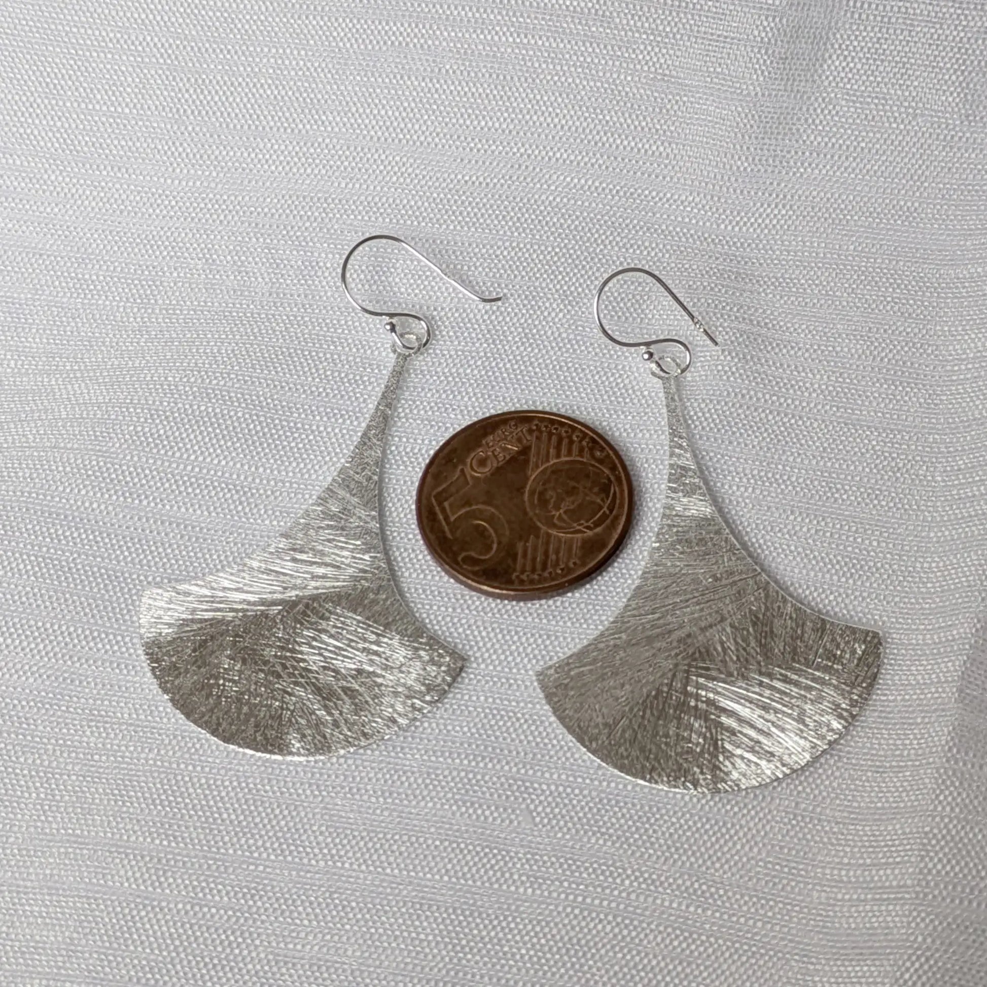 Größenvergleich der strukturierten Silber-Ohrhänger neben einer Münze.