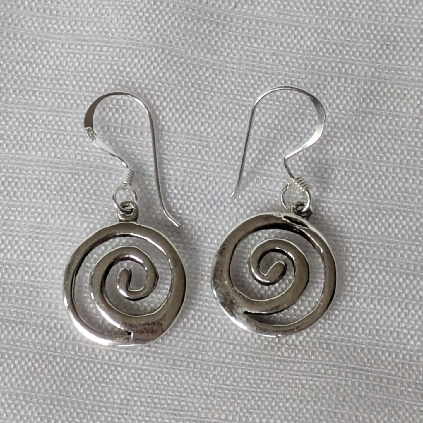 Paarweise Frontalansicht der runden Silberohrringe mit Spiral-Motiv.