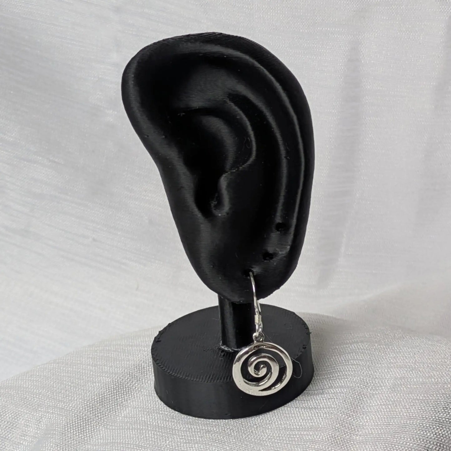 Elegante Präsentation der Spiral-Ohrringe an einem schwarzen Schmuckhalter.