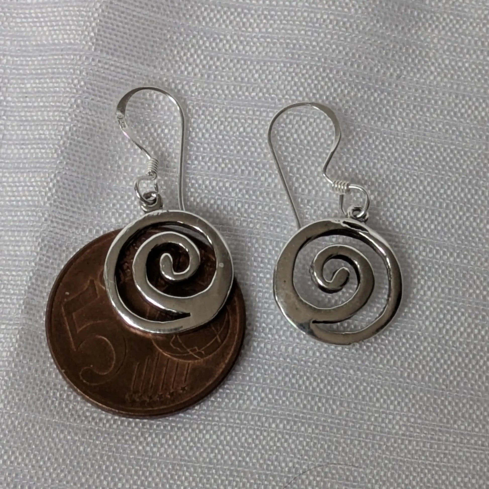 Größenvergleich der silbernen Spiral-Ohrhänger auf einer 5-Cent-Münze.