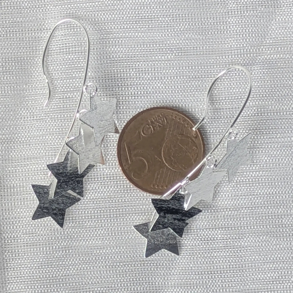 Größenvergleich: Lange, mattierte Stern-Ohrhänger aus 925 Silber liegend auf einer 5-Cent-Münze.