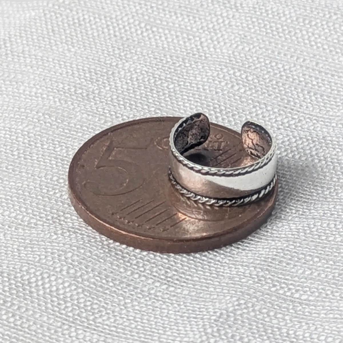 Größenvergleich: Die breite 925 Silber Ohrklemme mit Kordelmuster liegt flach auf einer 5-Cent-Münze.