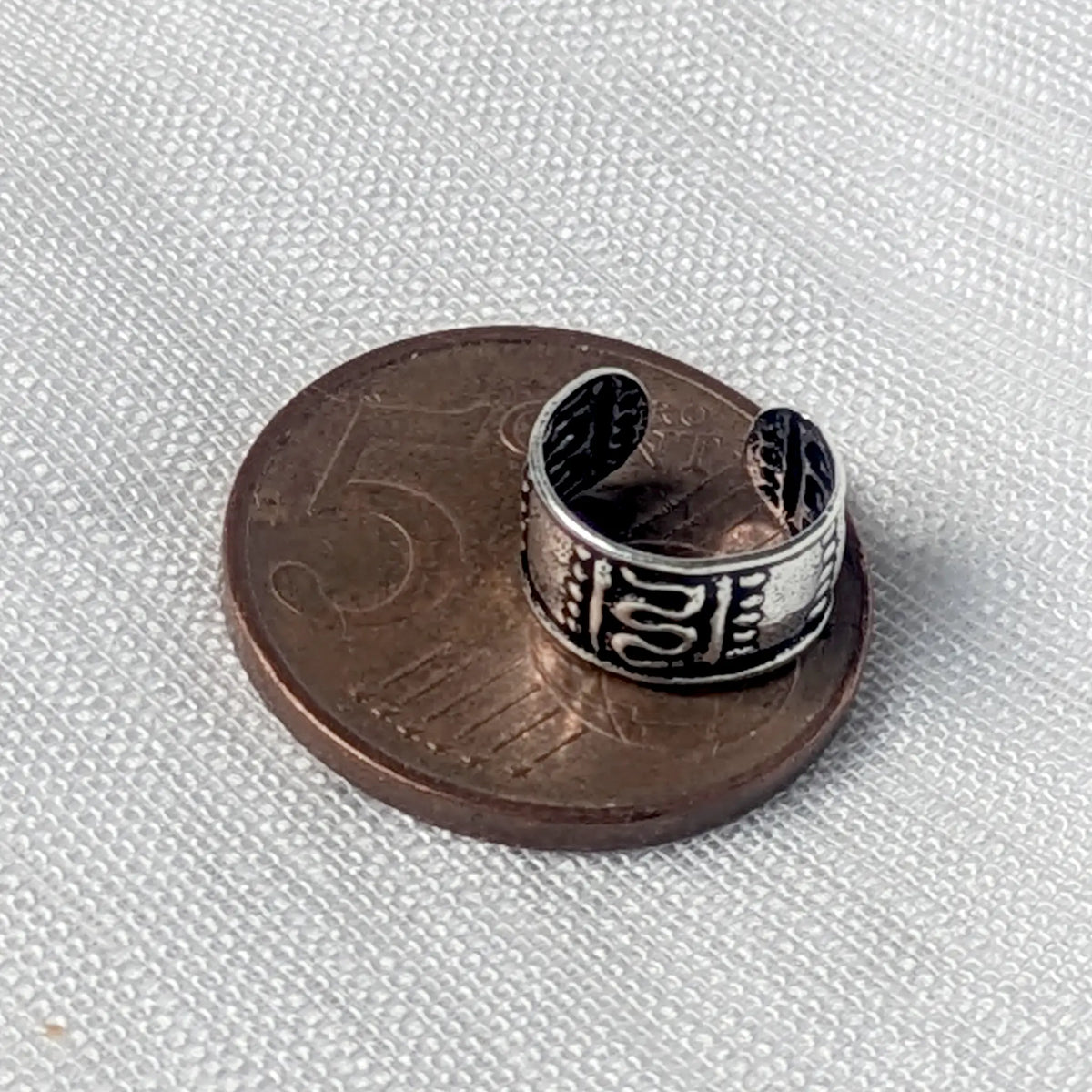 Größenvergleich: Ein breiter 925 Silber Ear Cuff im Antik-Design liegend auf einer 5-Cent-Münze.
