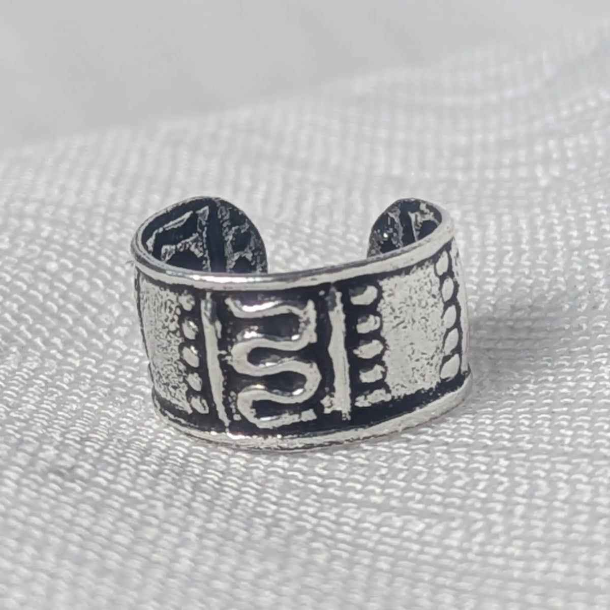 Nahaufnahme eines breiten 925 Silber Ear Cuffs mit geschwärztem Antik-Finish und verziertem S-Muster.