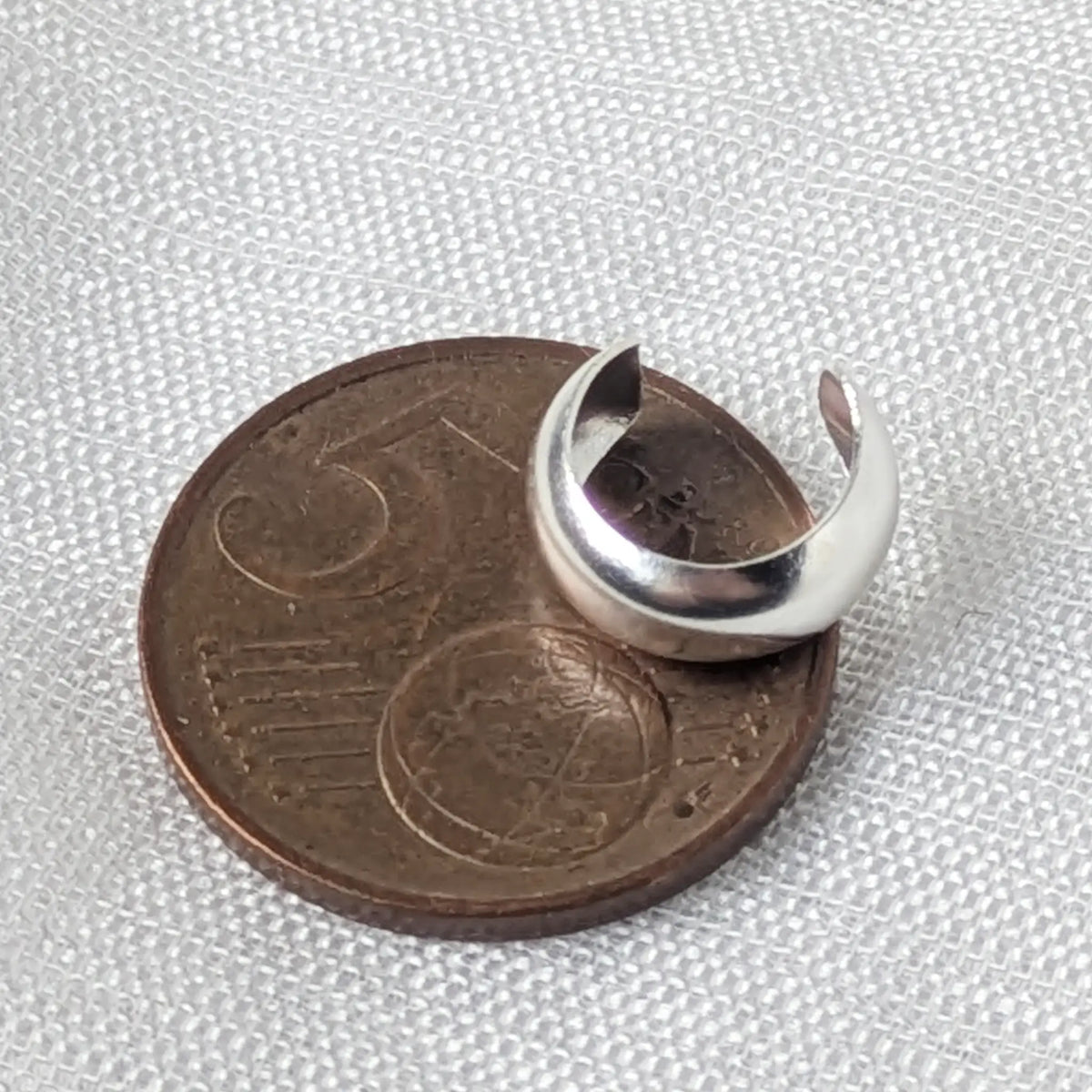 chlichter, breiter Silber-Earcuff liegend auf einer 5-Cent-Münze zur genauen Veranschaulichung der Größe.
