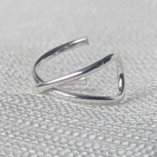 Nahaufnahme einer minimalistischen 925 Silber Ohrklemme mit hochglanzpolierter, gekreuzter X-Form.