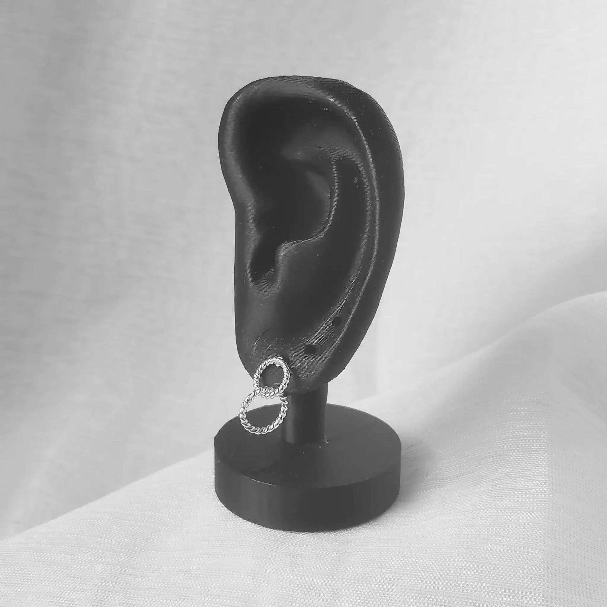 Die verschlungenen Silber-Ohrringe 925 präsentiert an einem schwarzen Ohr-Modell zur Veranschaulichung der optimalen Passform und Größe