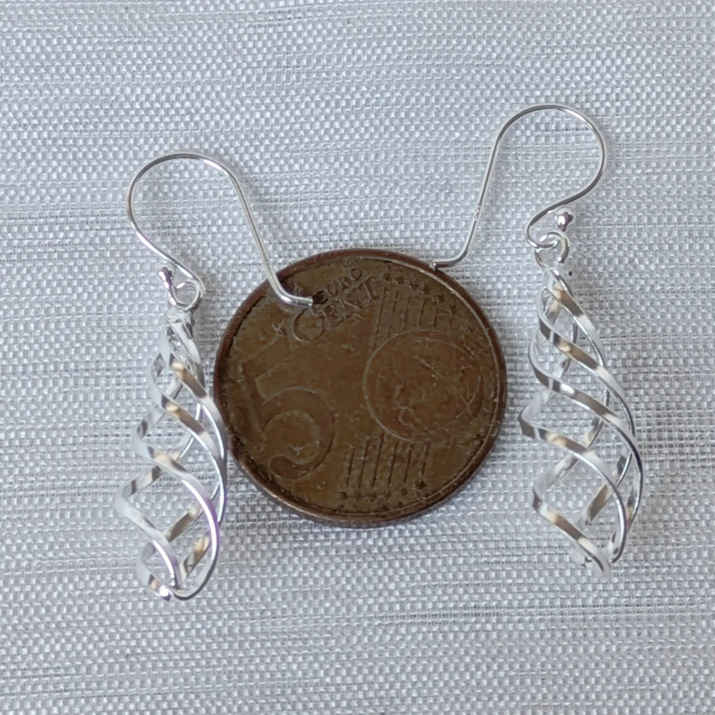 Größenvergleich der silbernen Spiral-Ohrhänger neben einer 5-Cent-Münze.