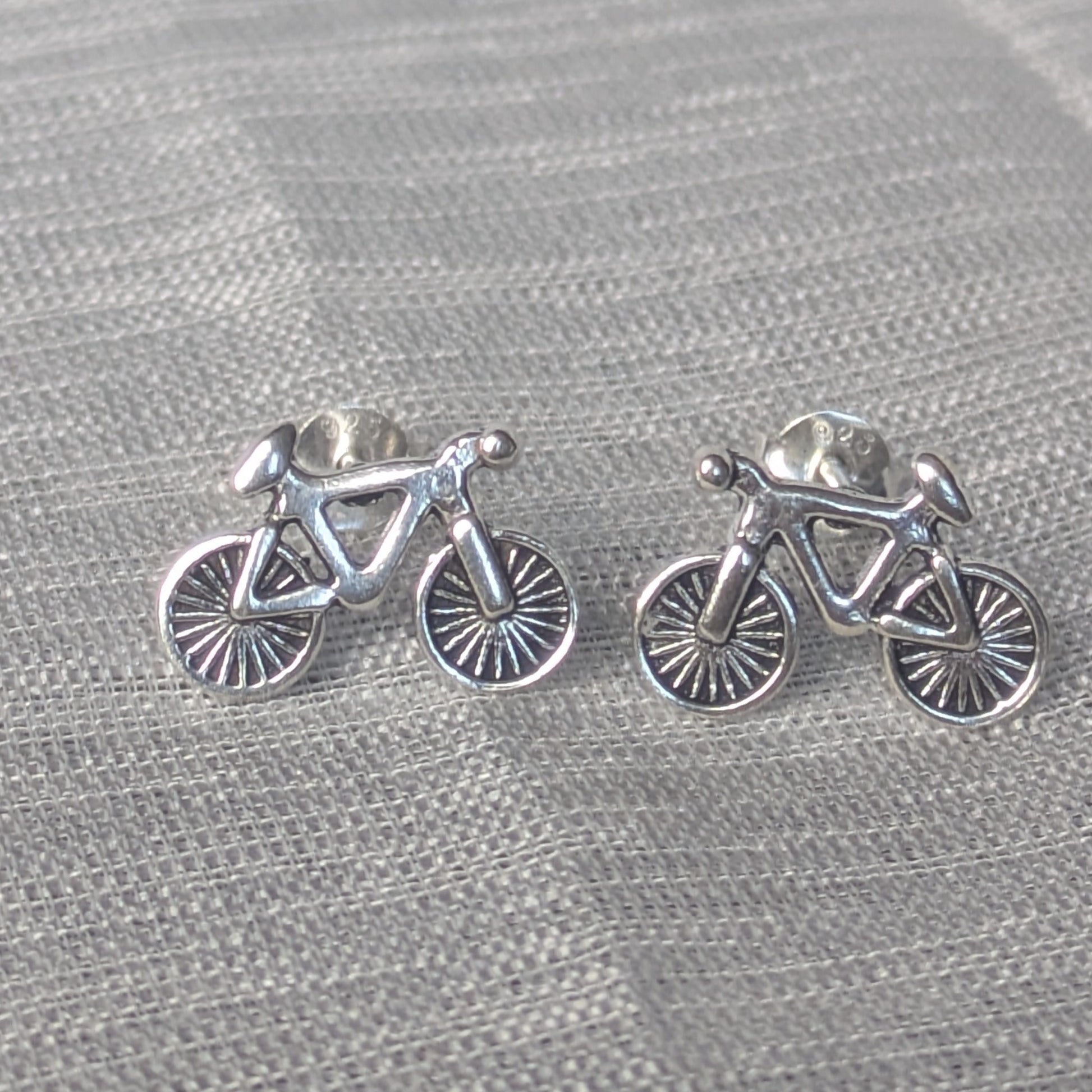 Fahrrad Ohrstecker aus 925 Silber – detailreiche Damen Ohrringe auf Stoffhintergrund