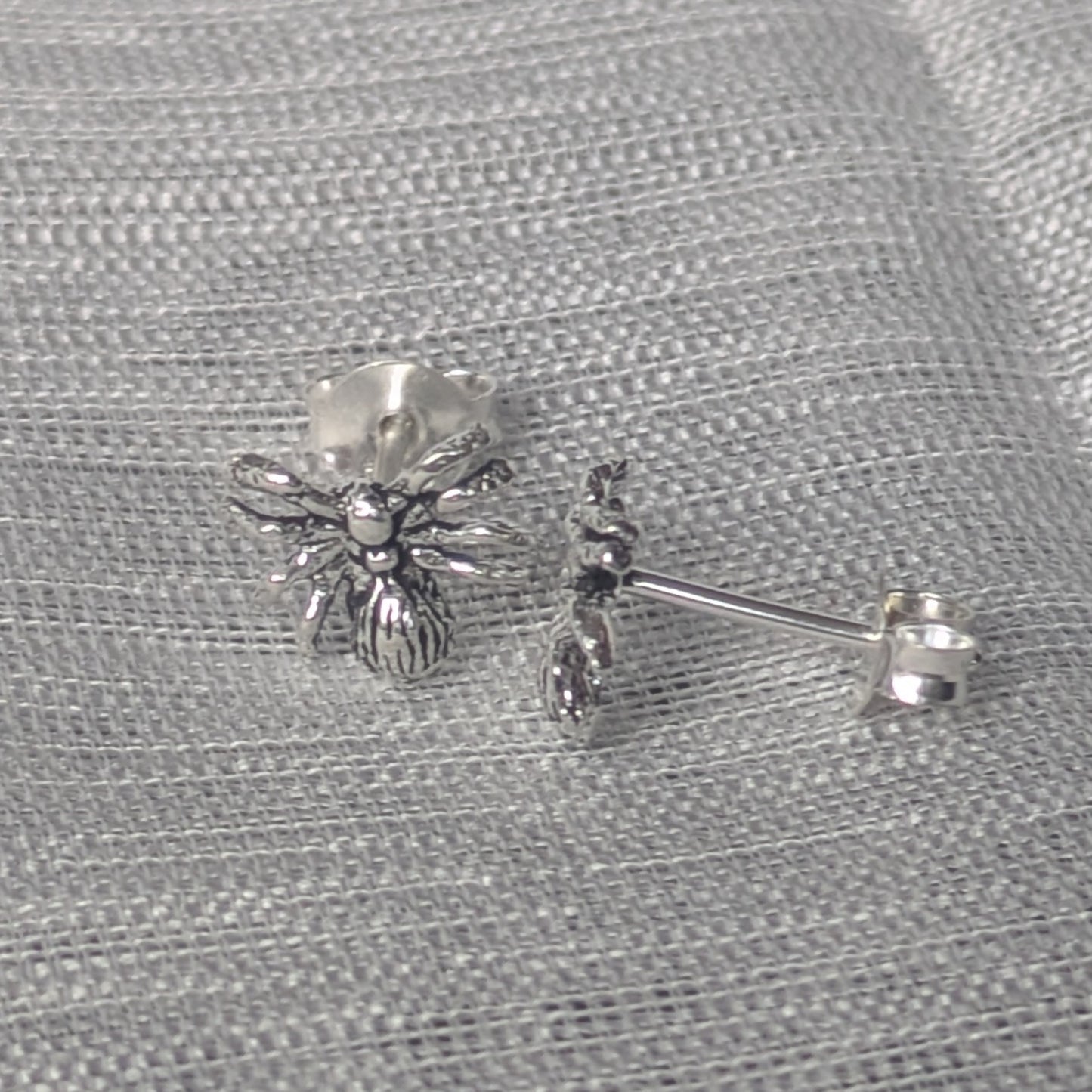 Detailreiche Spinnen‑Ohrstecker aus Sterling Silber, frontal fotografiert.