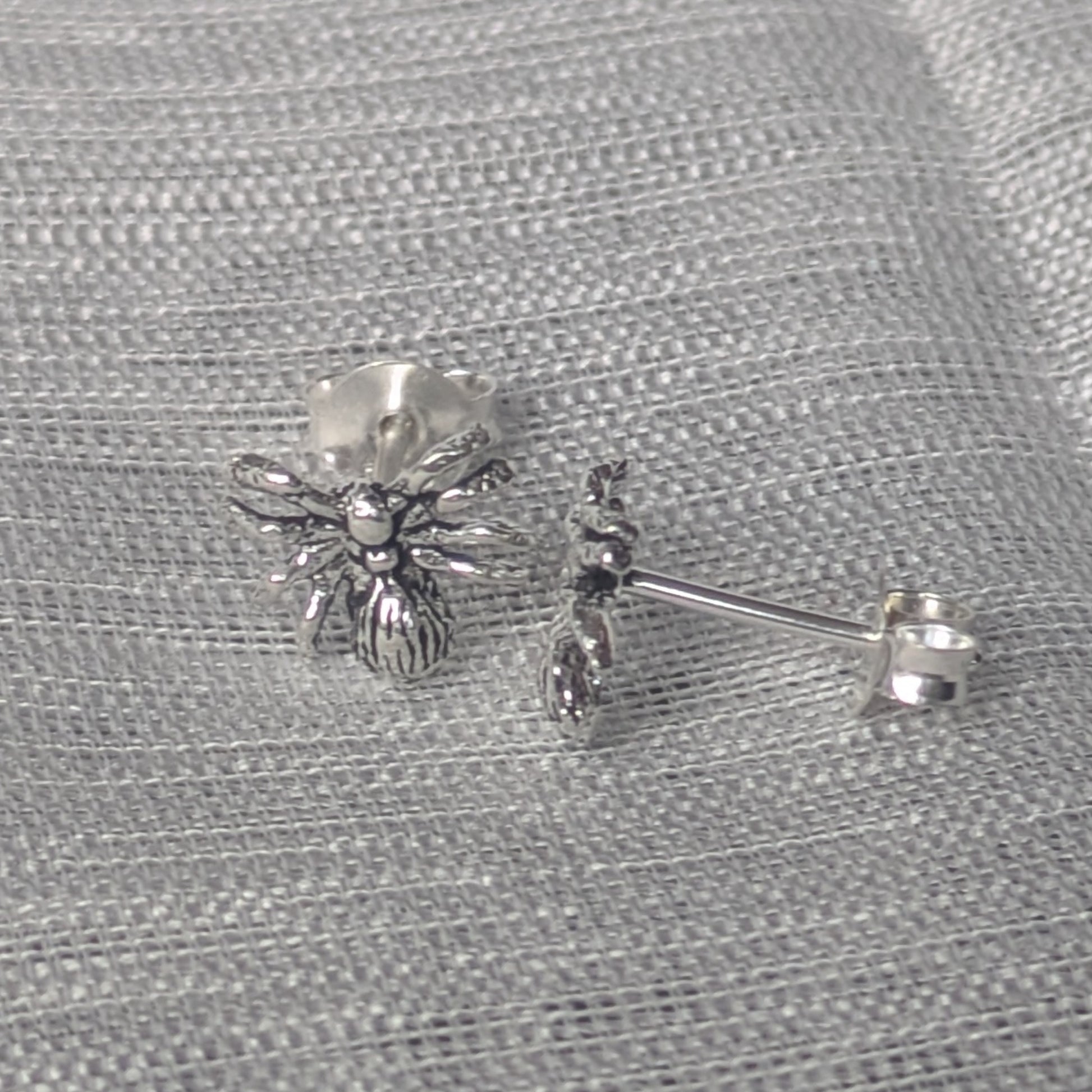 Detailreiche Spinnen‑Ohrstecker aus Sterling Silber, frontal fotografiert.