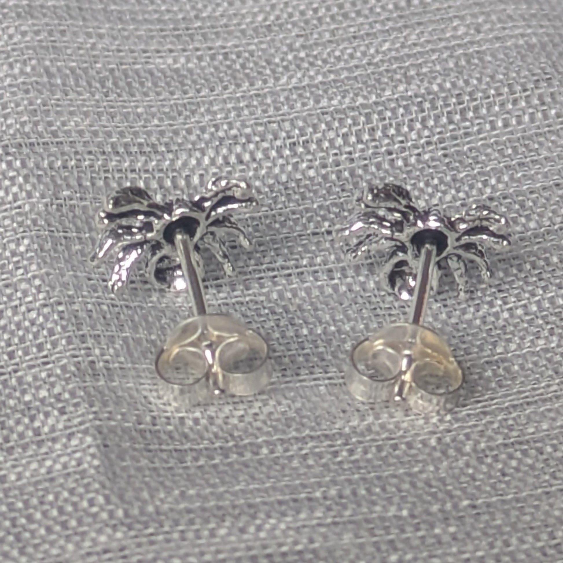 925‑Silber‑Ohrstecker im Spinnen‑Design, hintere Ansicht auf Textiluntergrund platziert.