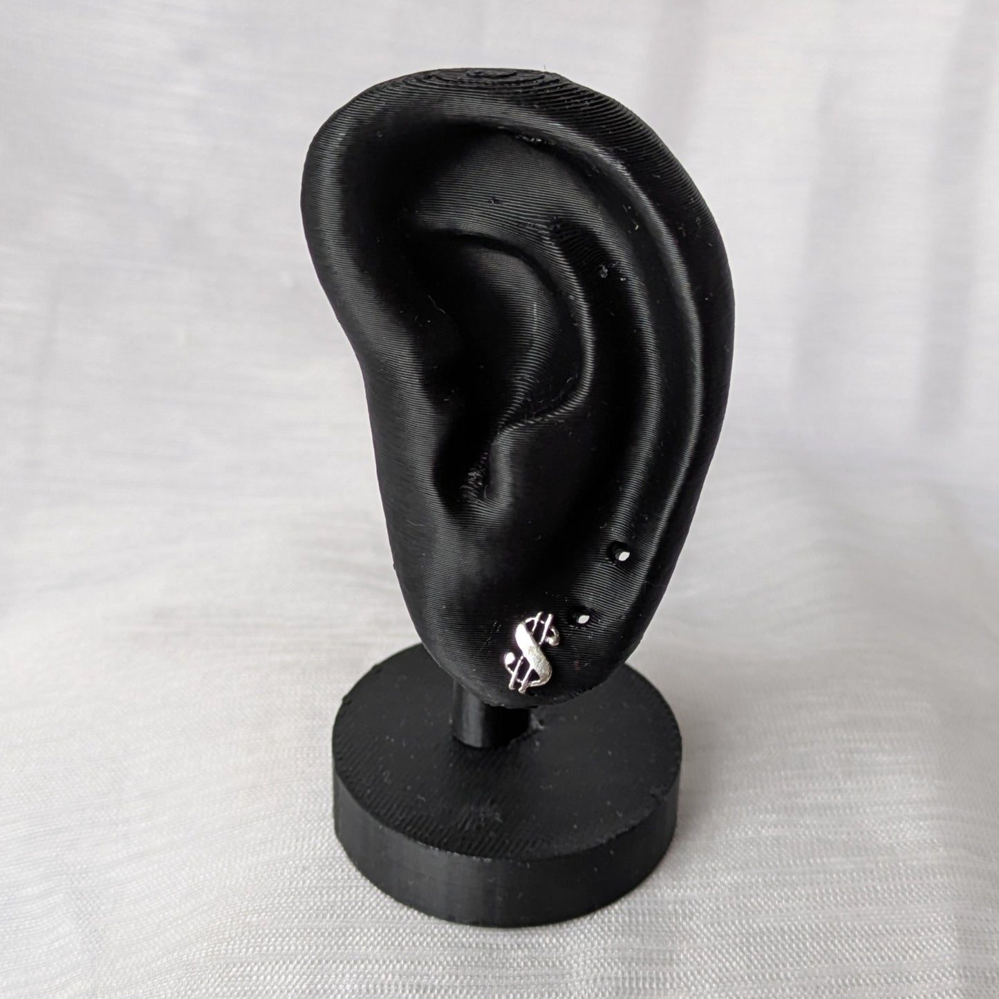 Elegante Dollar-Ohrstecker präsentiert auf einem schwarzen Schmuck-Display.