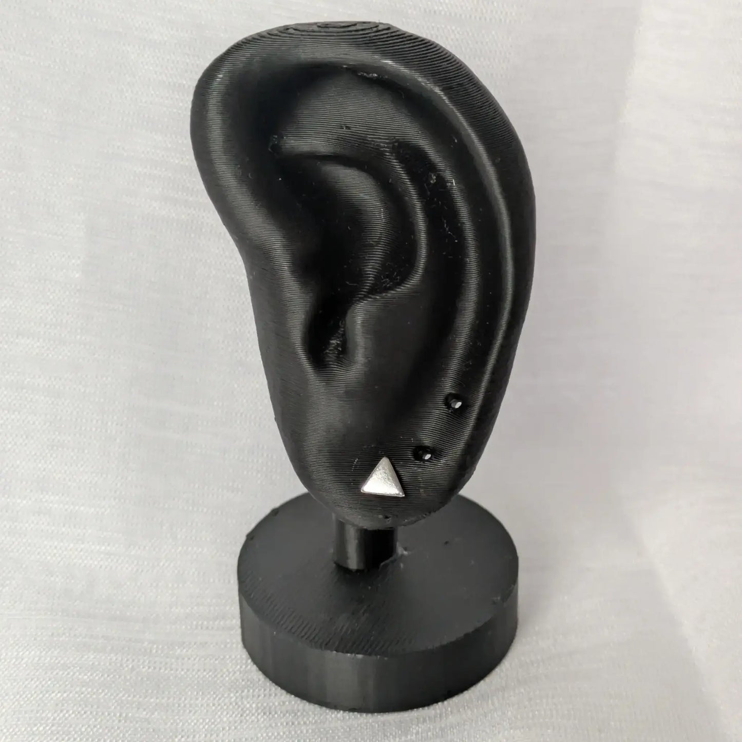 Silberne Dreieck-Ohrstecker am schwarzen Schmuck-Display präsentiert