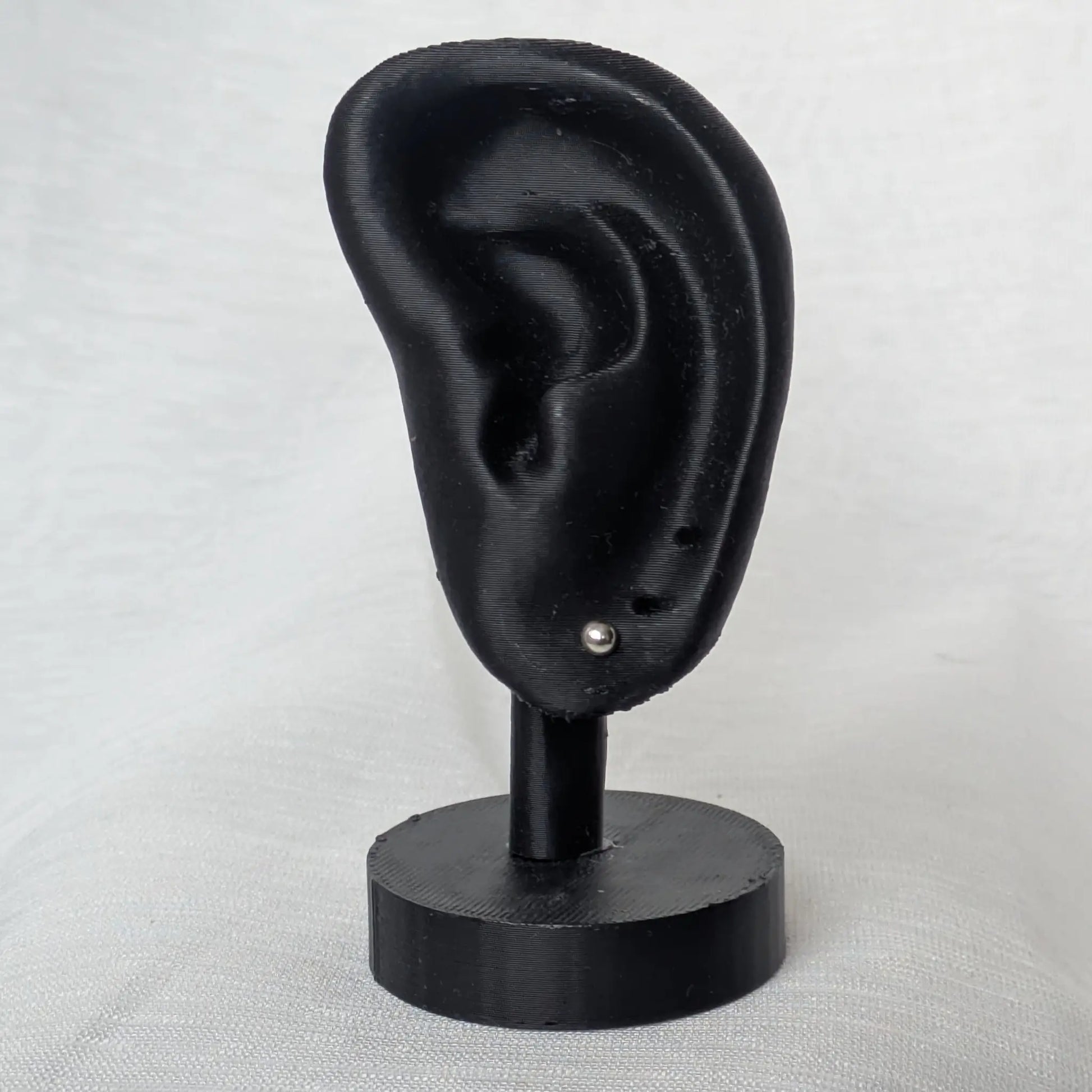 3mm Halbkugel Ohrstecker Silber am schwarzen Ohr-Modell präsentiert.