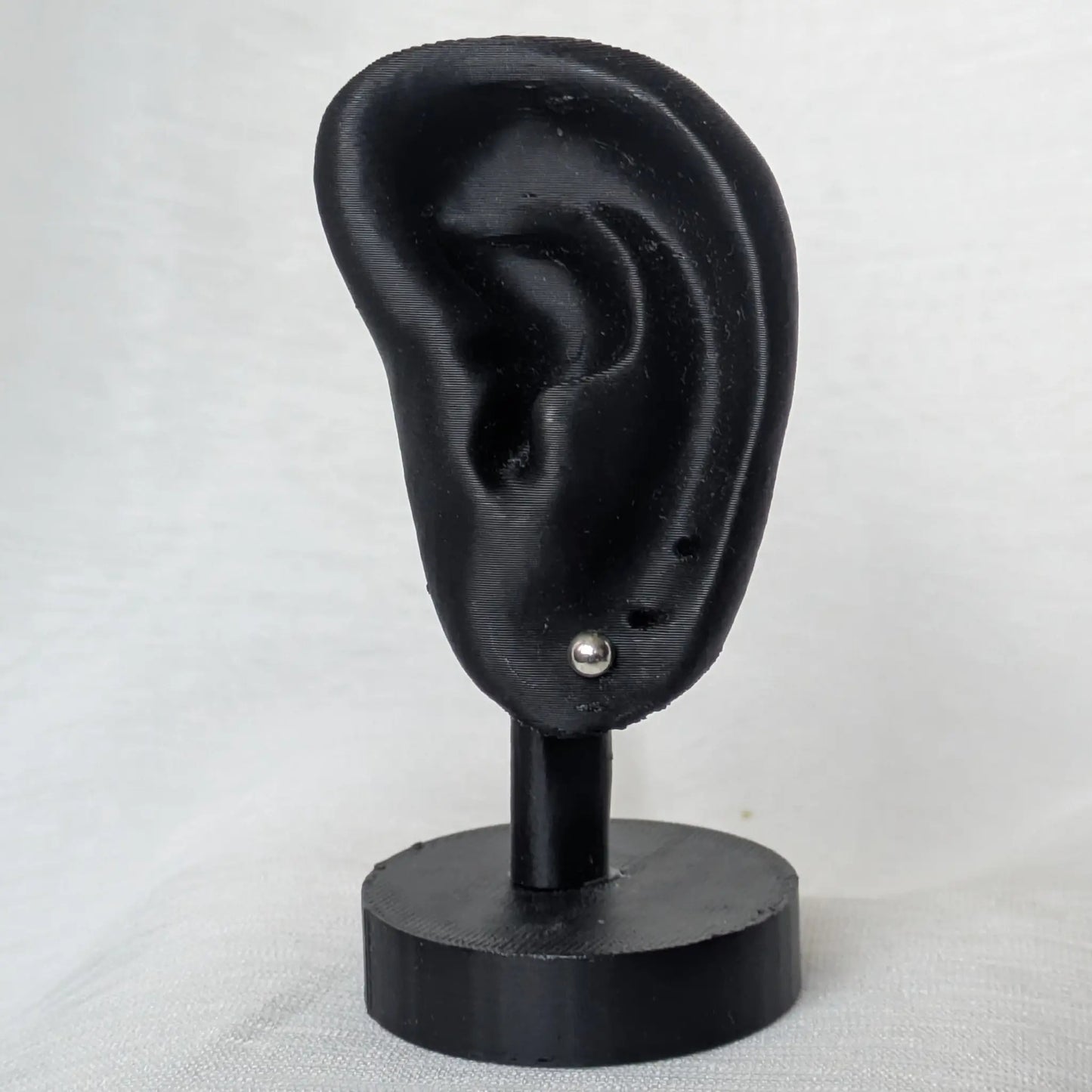 4mm Halbkugel Ohrstecker Silber am schwarzen Ohr-Modell präsentiert.