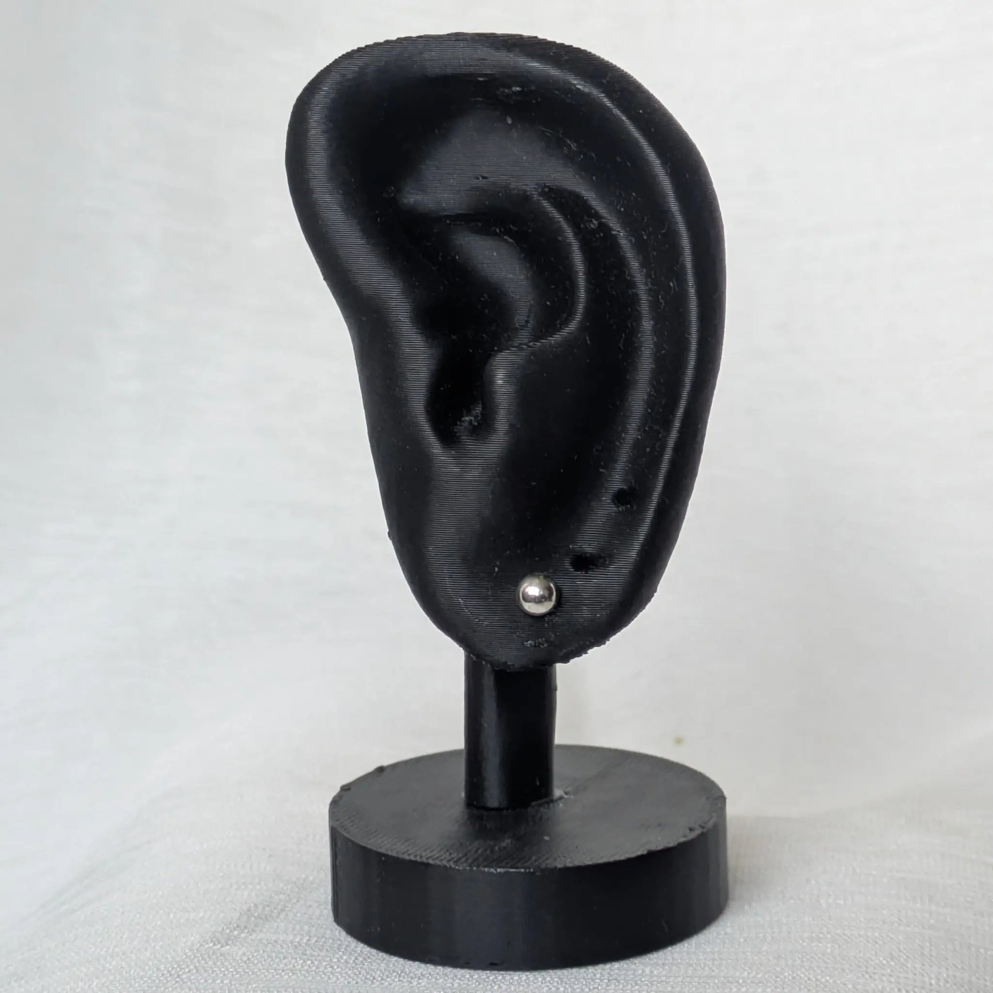 4mm Halbkugel Ohrstecker Silber am schwarzen Ohr-Modell präsentiert.