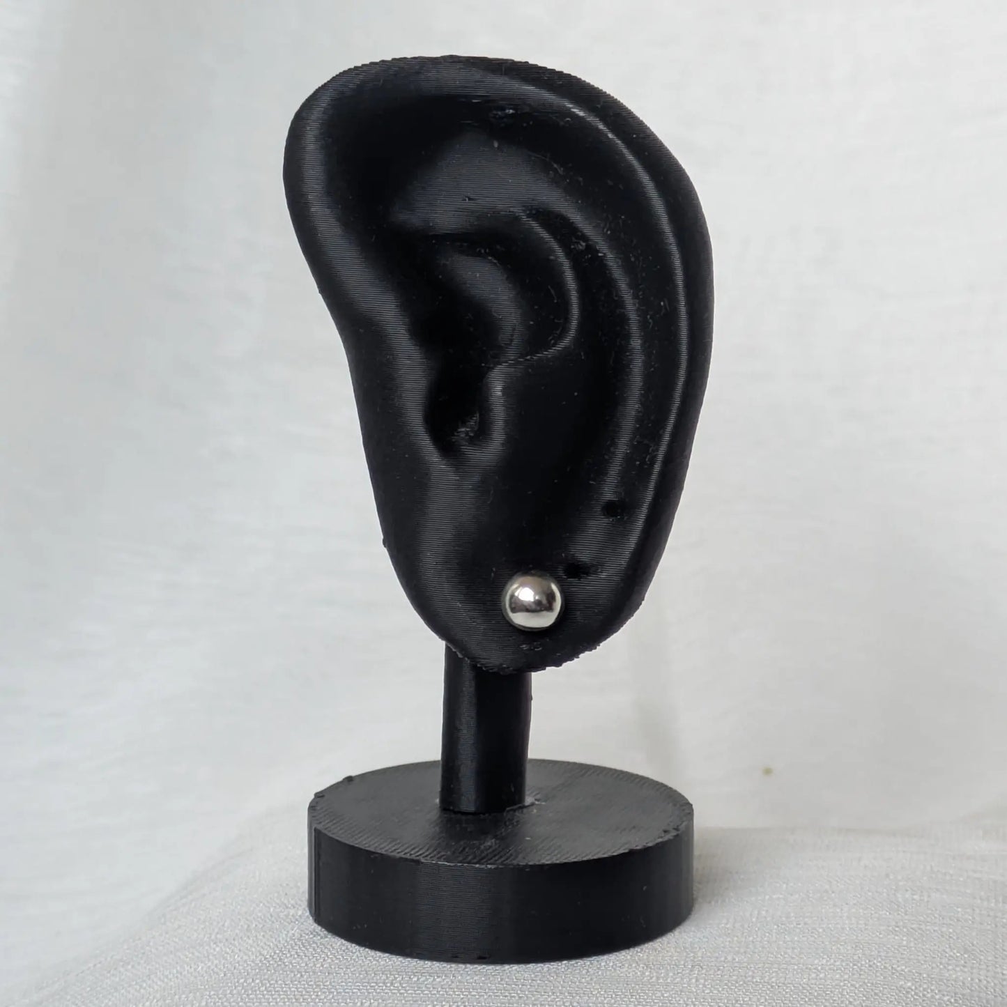 6mm Halbkugel Ohrstecker Silber am schwarzen Ohr-Modell präsentiert.
