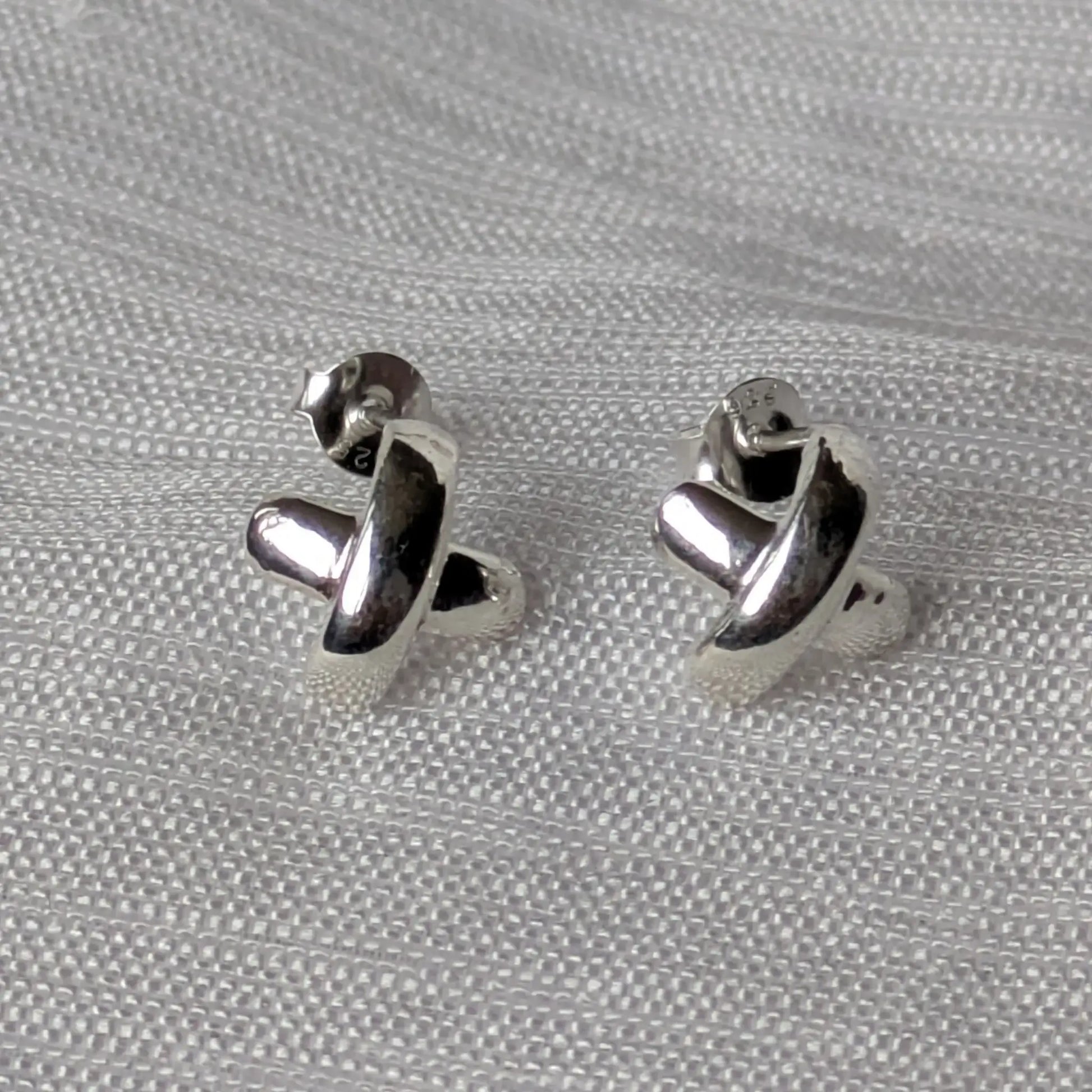Frontalansicht der symmetrischen X-Form Silberohrstecker für Damen.