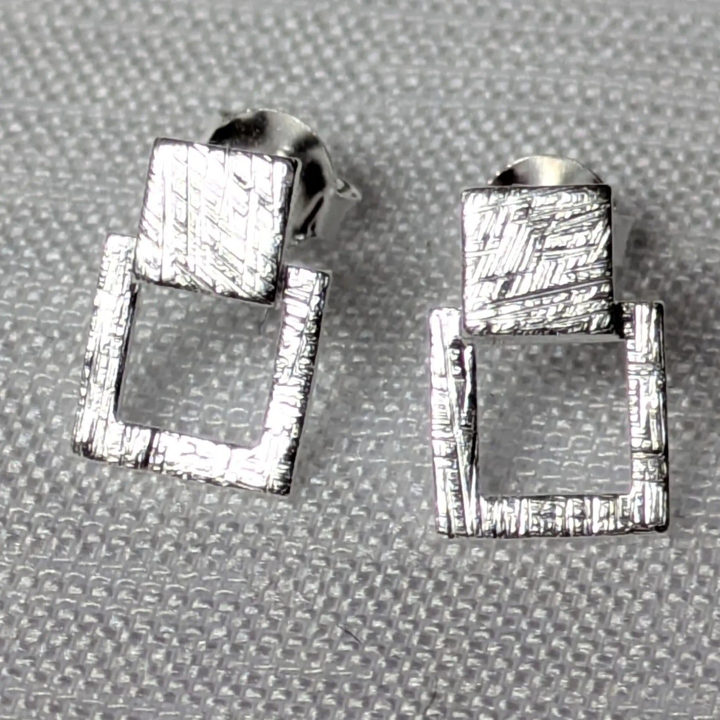 Detailansicht der strukturierten Oberfläche der silbernen Quadrat-Ohrstecker.