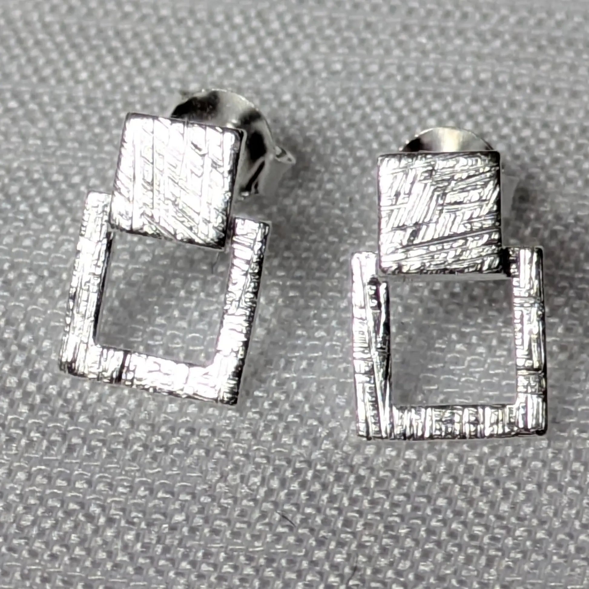 Detailansicht der strukturierten Oberfläche der silbernen Quadrat-Ohrstecker.