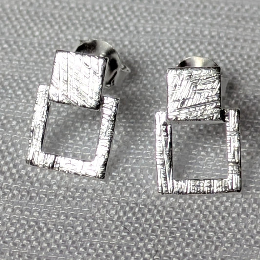 Detailansicht der strukturierten Oberfläche der silbernen Quadrat-Ohrstecker.