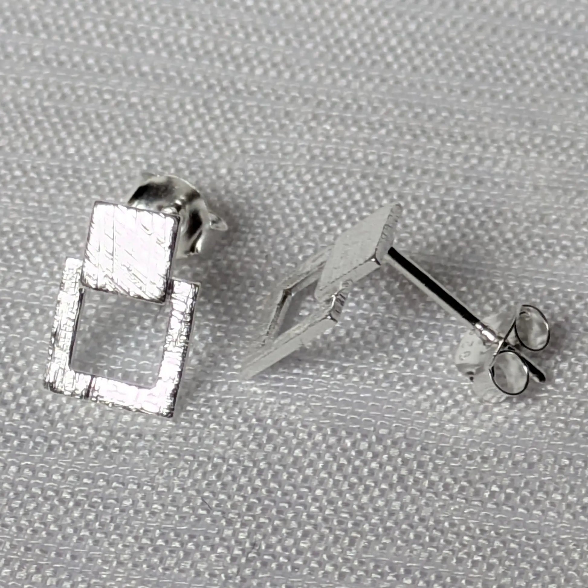 Seitenprofil der silbernen Ohrstecker zur Darstellung der Materialstärke und Struktur.