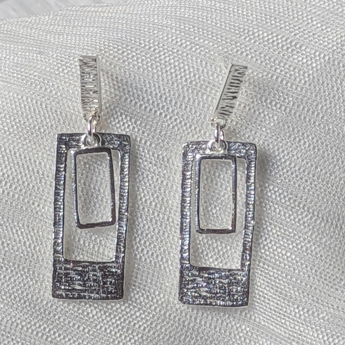 Nahaufnahme hängende 925 Silber Ohrstecker, markantes geometrisches Doppel-Rechteck-Design mit strukturierter Oberfläche.