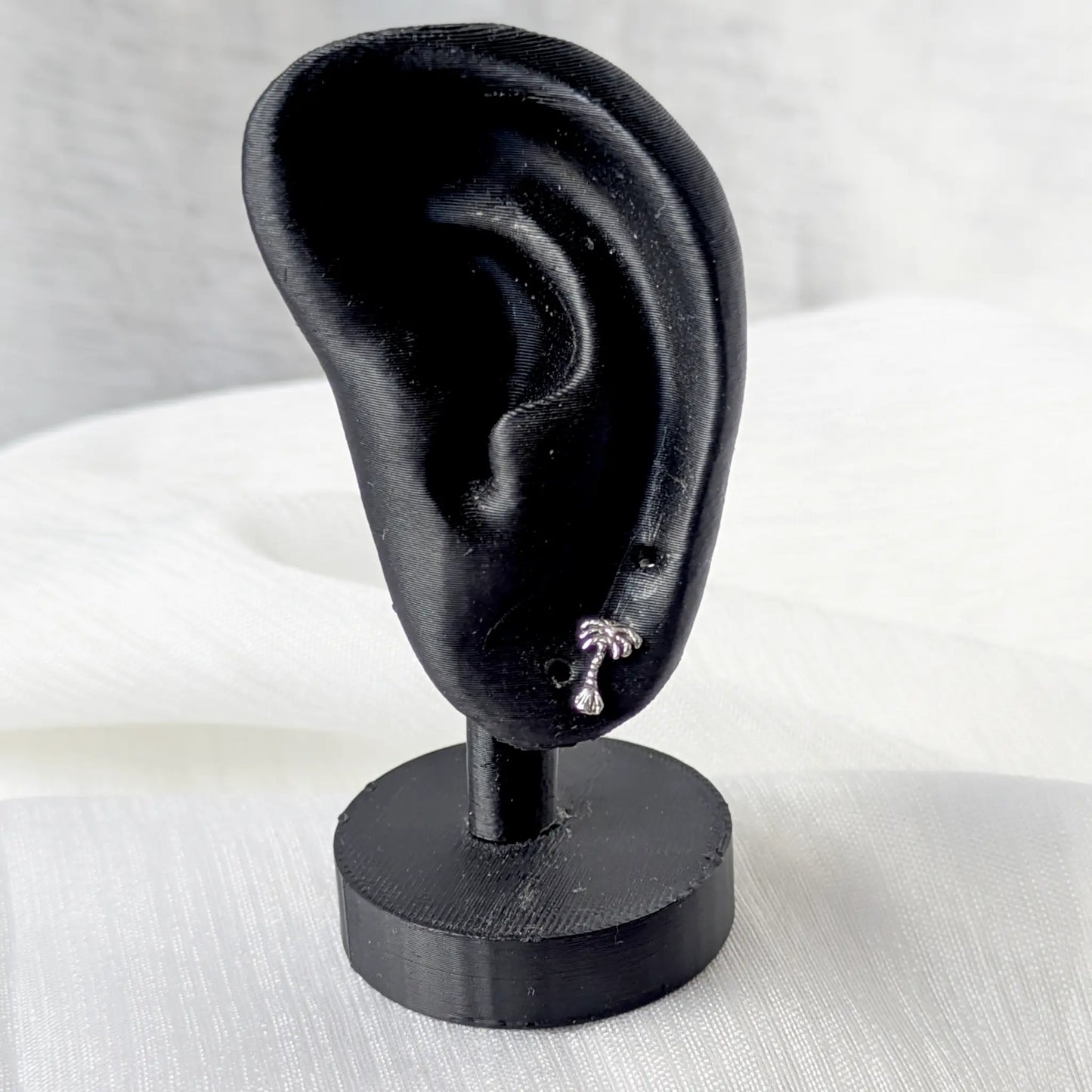 Palmen Ohrstecker aus 925 Silber am Ohrläppchen eines schwarzen Ohr-Displays