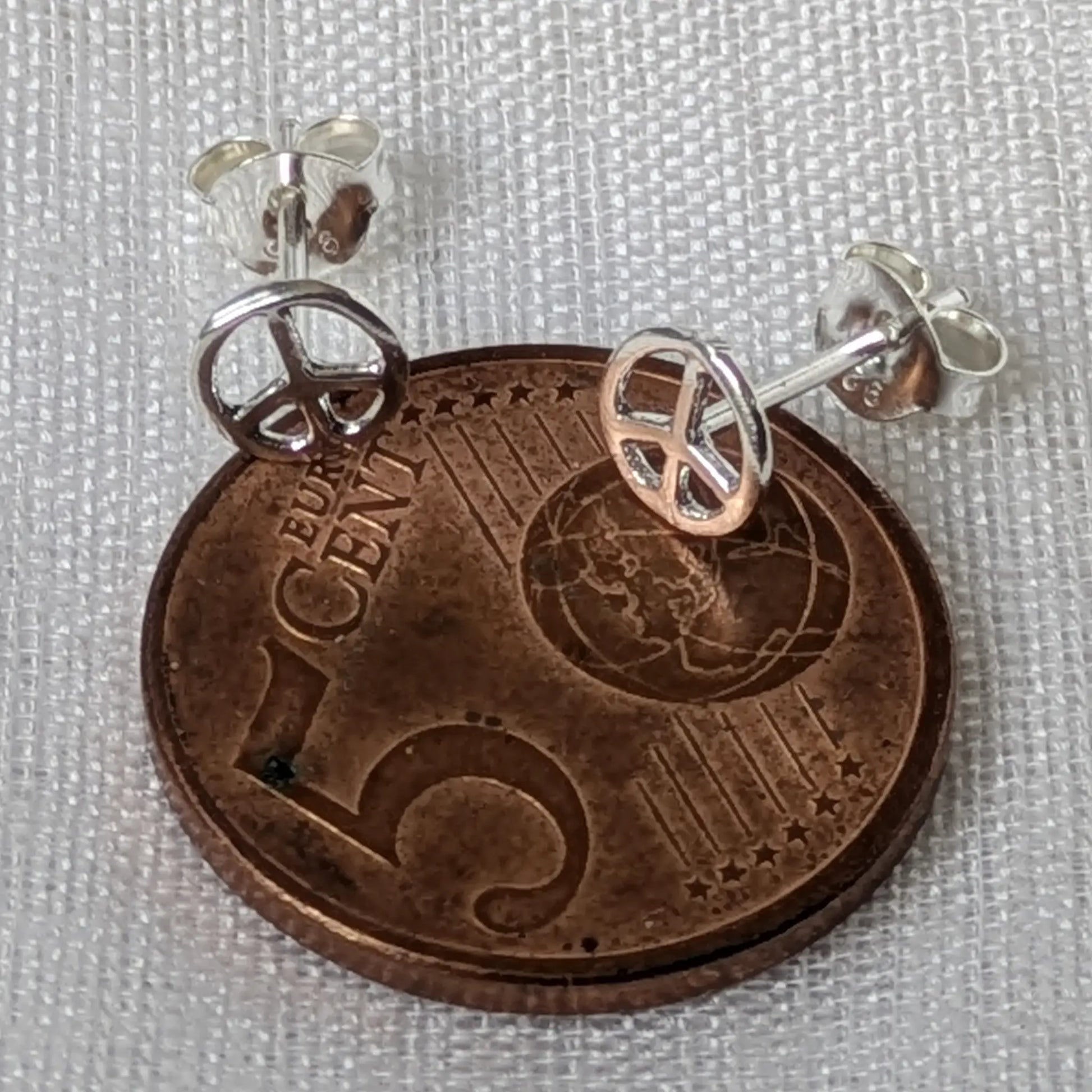 Größenvergleich der kleinen Peace Ohrstecker 925 Silber direkt auf einer 5-Cent-Münze