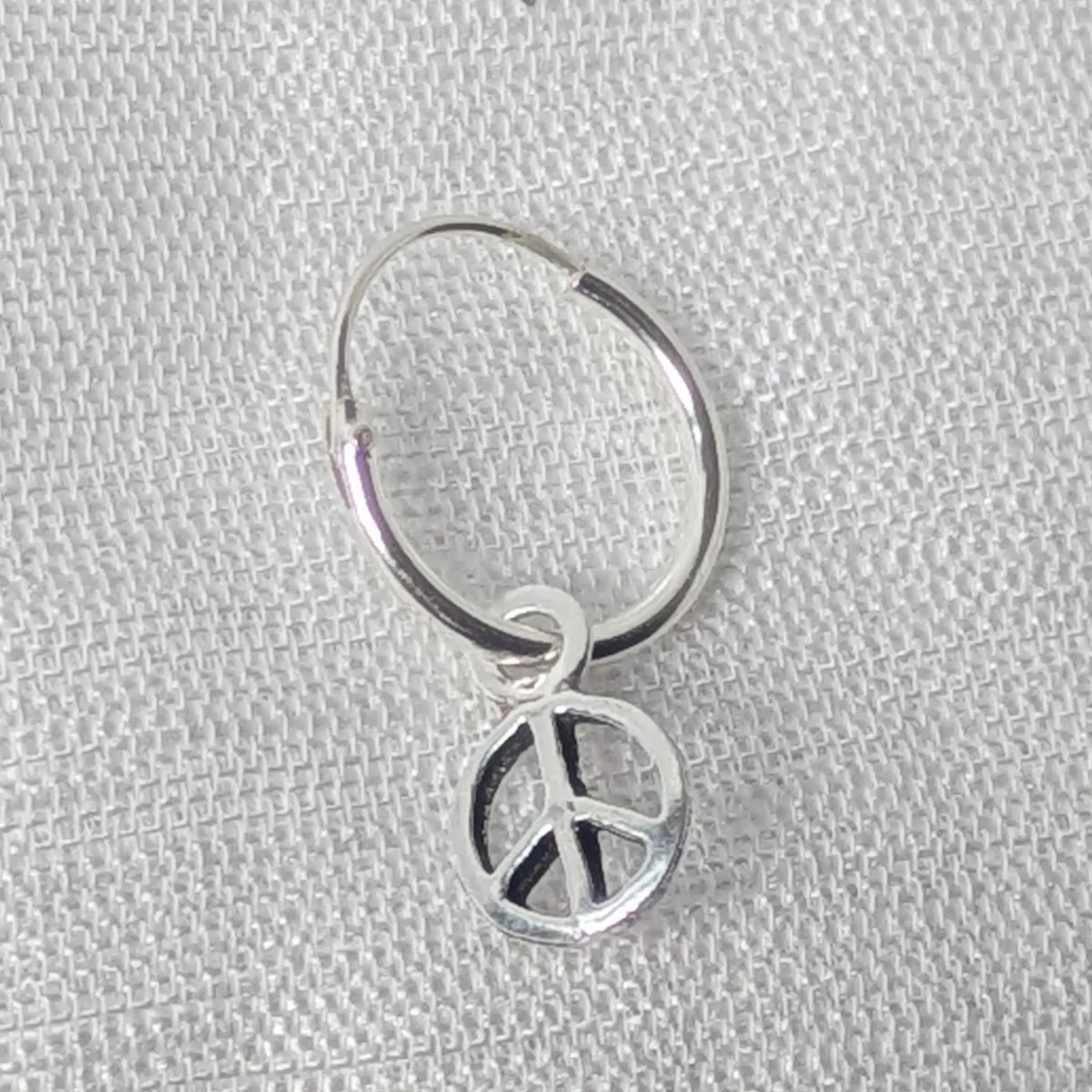 Detaillierte Nahaufnahme einer 925 Silber Creole mit feinem Peace-Zeichen Anhänger.