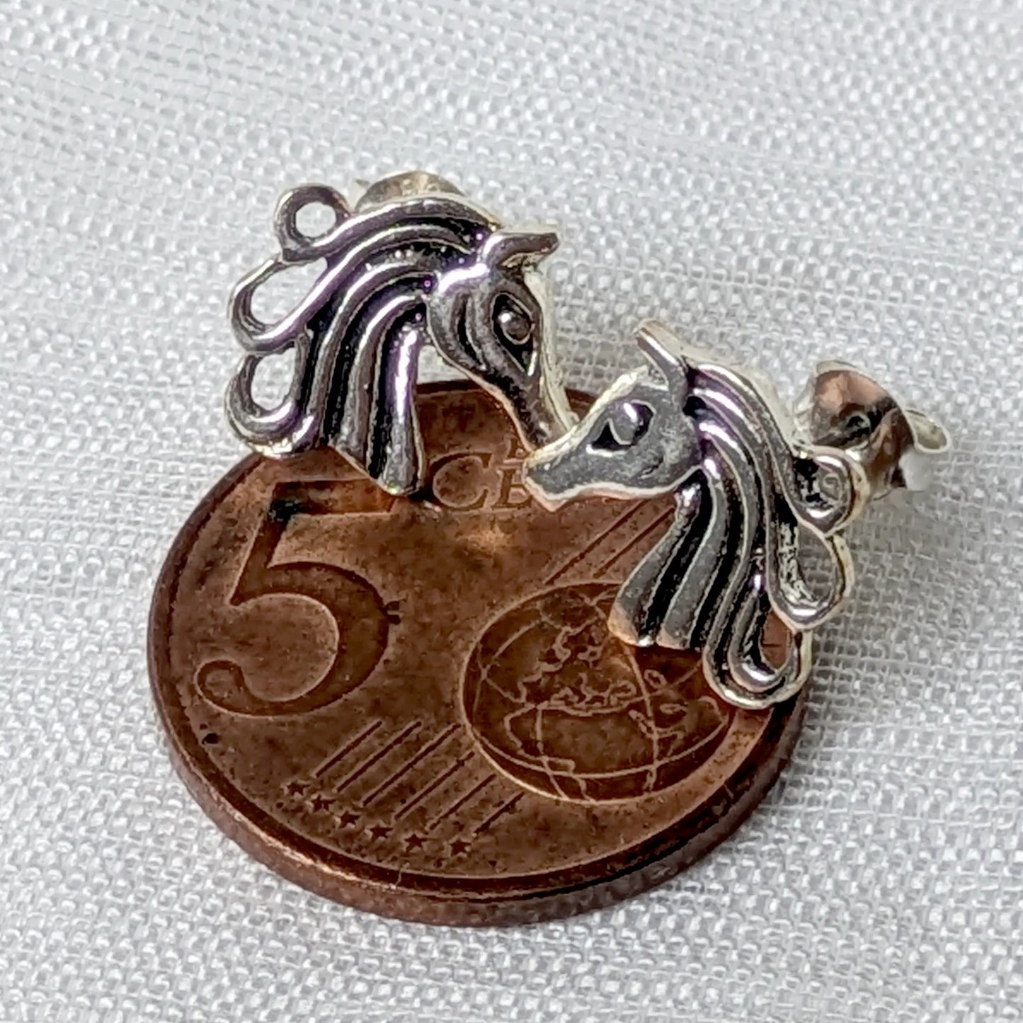 Größenvergleich der zierlichen Pferdekopf-Ohrstecker aus Silber auf einer 5-Cent-Münze.