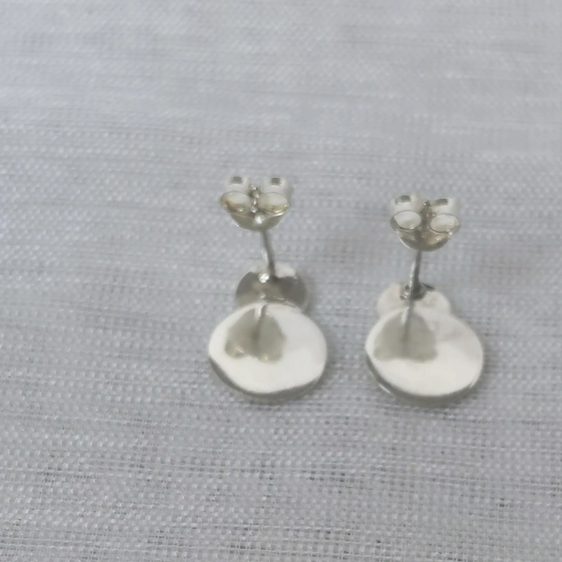 Rückseite der geometrischen Plättchen-Ohrringe aus Silber mit angebrachten Schmetterlingsverschlüssen für sicheren Halt.