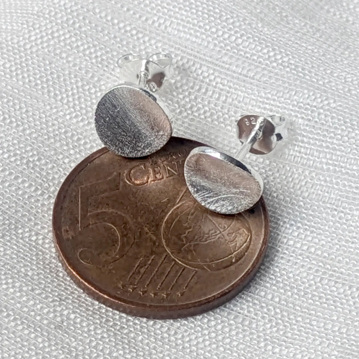 Größenvergleich: Flache, runde 925 Silber Plättchen-Ohrstecker liegend auf einer 5-Cent-Münze.

