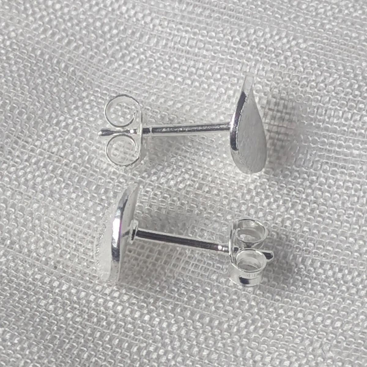Seitenansicht der flachen Silber Plättchen-Ohrstecker, sichtbar sind der gerade Befestigungsstift und der Schmetterlingsverschluss.