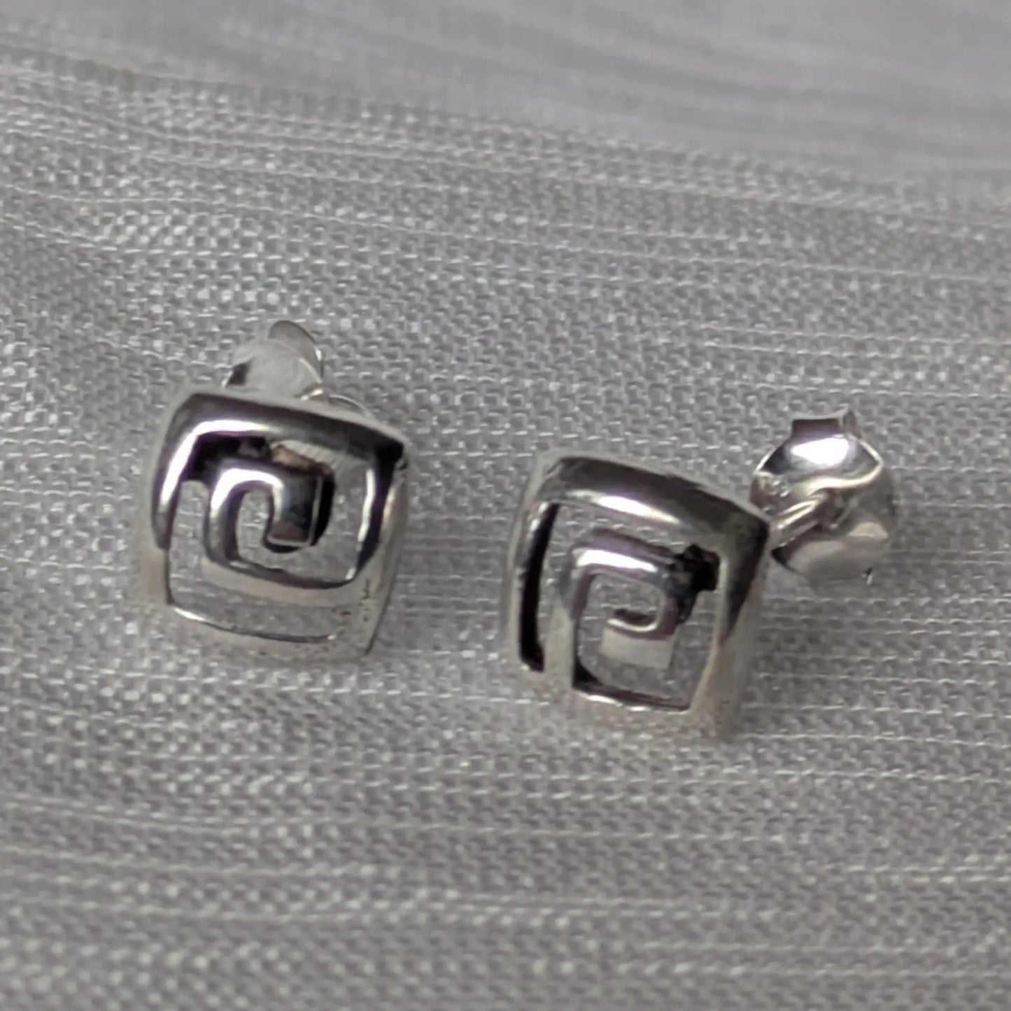 Paarweise Frontalansicht der quadratischen Silber-Ohrstecker mit Labyrinth-Design.