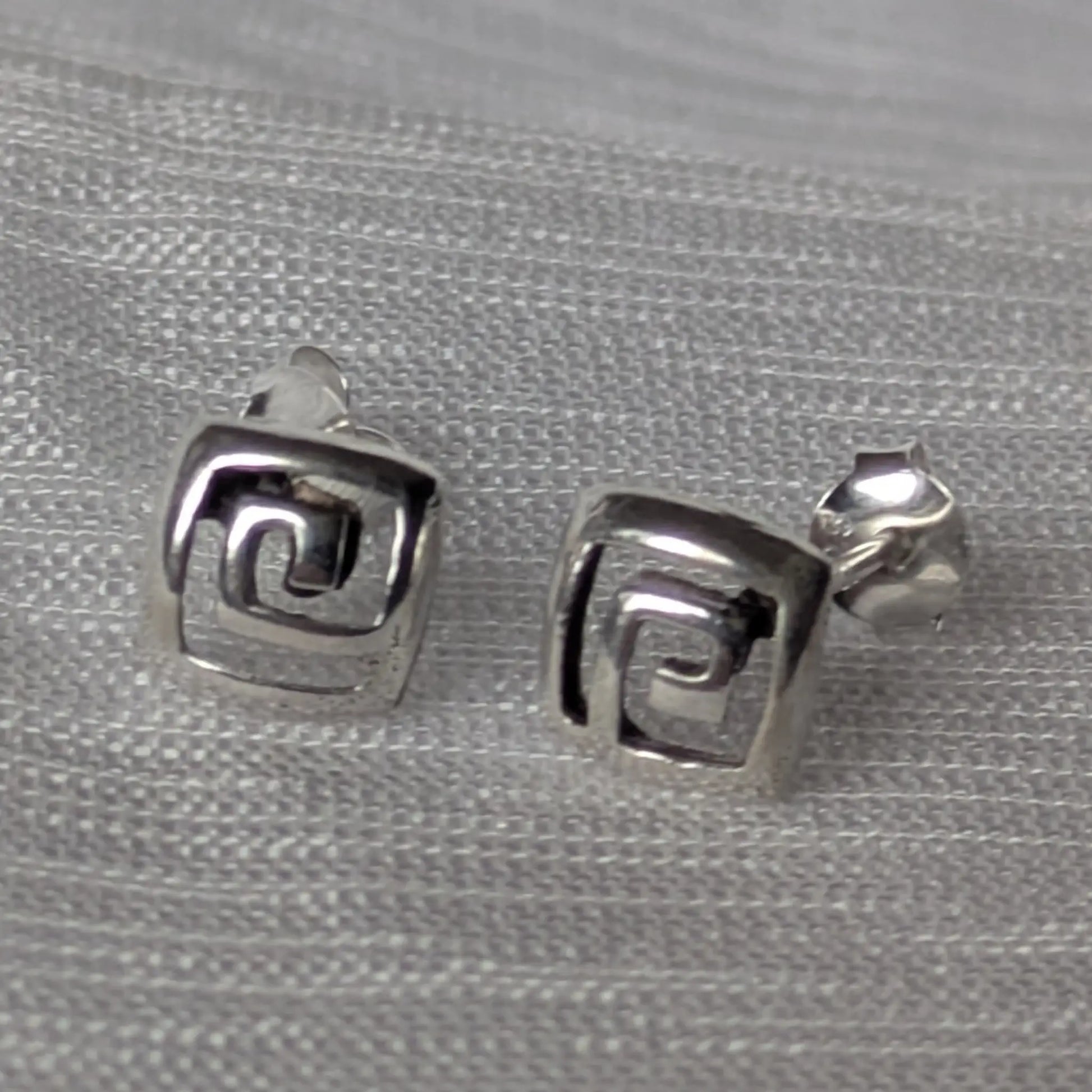 Paarweise Frontalansicht der quadratischen Silber-Ohrstecker mit Labyrinth-Design.