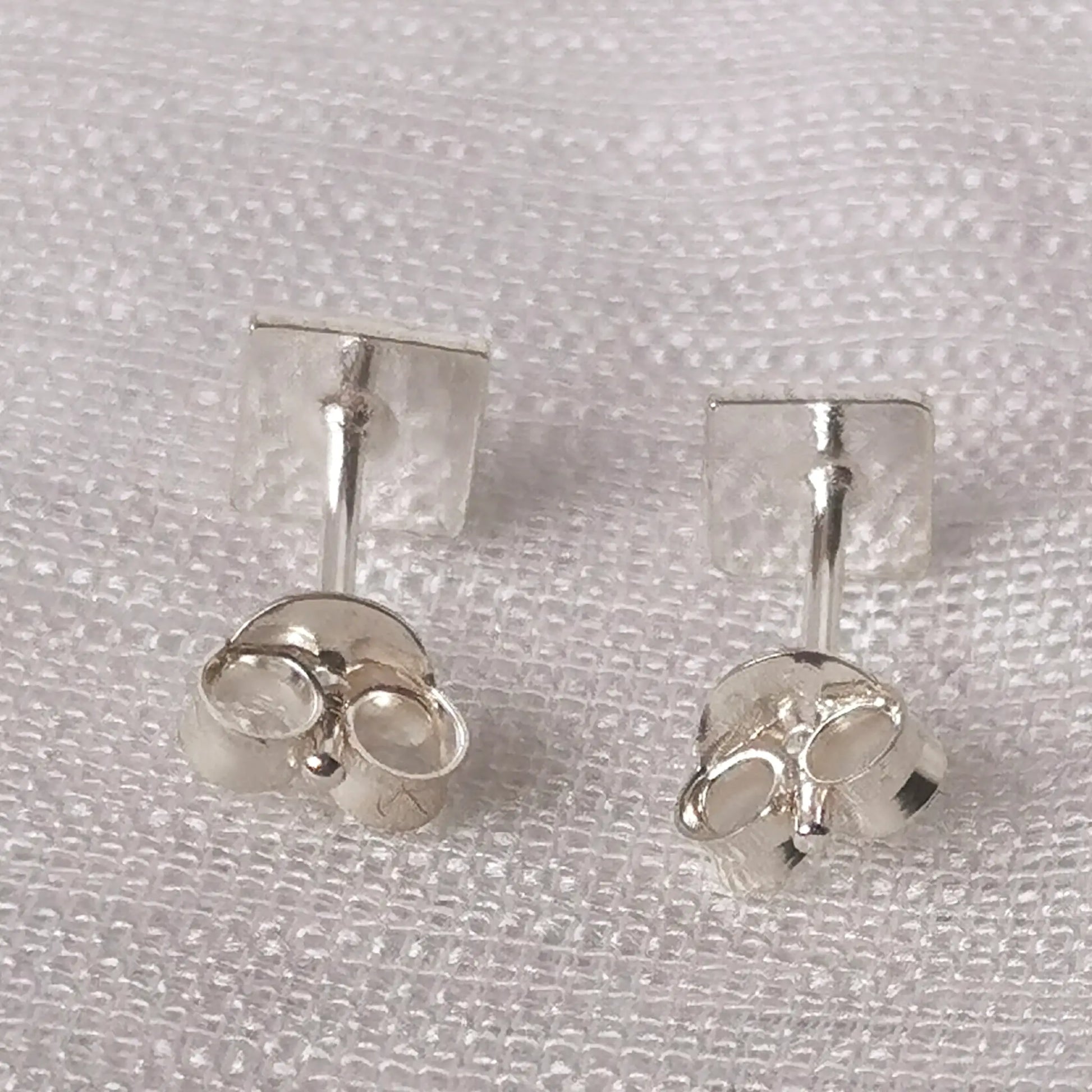Rückseite der gehämmerten Viereck-Ohrringe aus Echt-Silber mit den dazugehörigen Schmetterlingsverschlüssen.