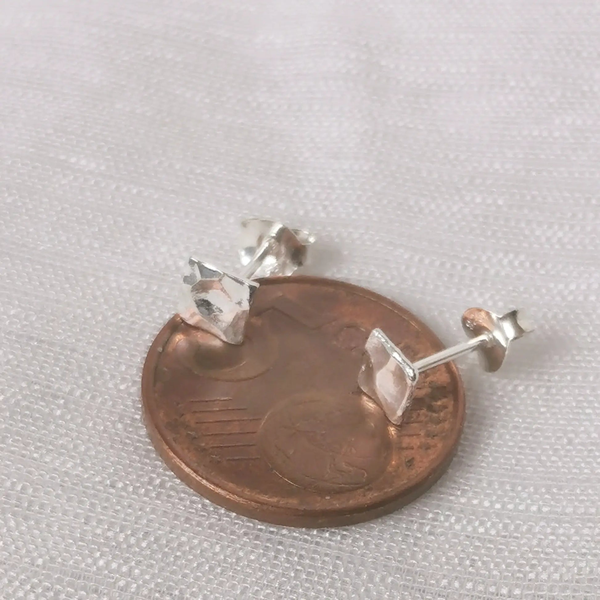 Größenvergleich der eckigen, gehämmerten 925er Silber-Ohrringe platziert auf einer 5-Cent-Münze.
