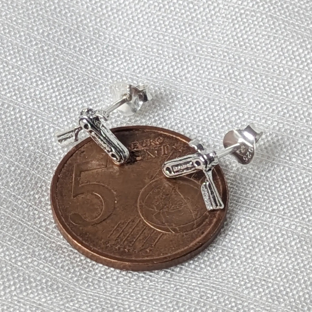 Silberner Rasiermesser-Ohrstecker flach auf einer 5-Cent-Münze liegend für einen realistischen Größenvergleich.