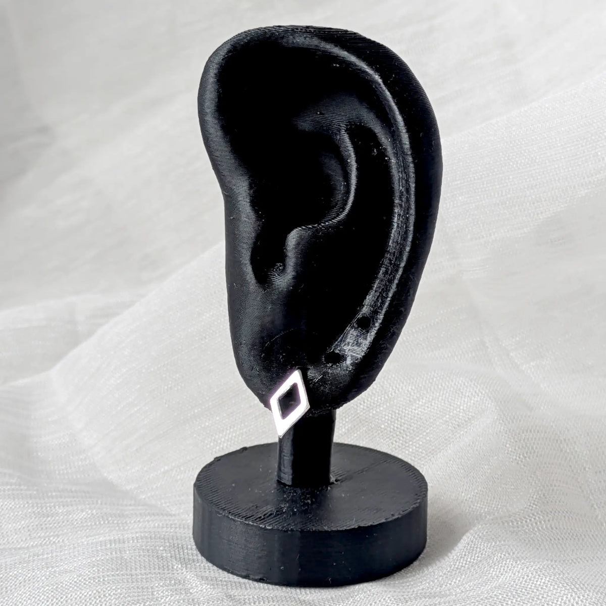 Frontalansicht der Rauten-Silberohrstecker, die das durchbrochene, eckige Design und die Materialtextur deutlich zeigt.