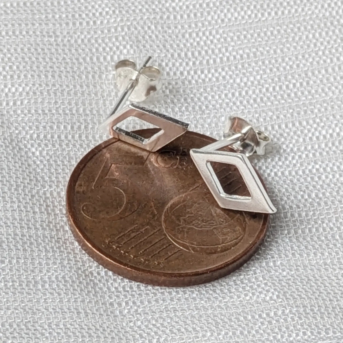 Größenvergleich der filigranen, offenen Rauten-Ohrstecker aus Silber, flach liegend auf einer 5-Cent-Münze.