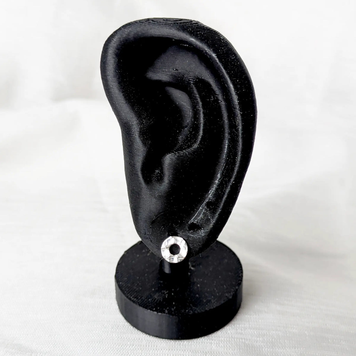 Gehämmerter 925 Silber Kreis-Ohrstecker präsentiert an einem schwarzen Ohr-Display zur Veranschaulichung der Passform.